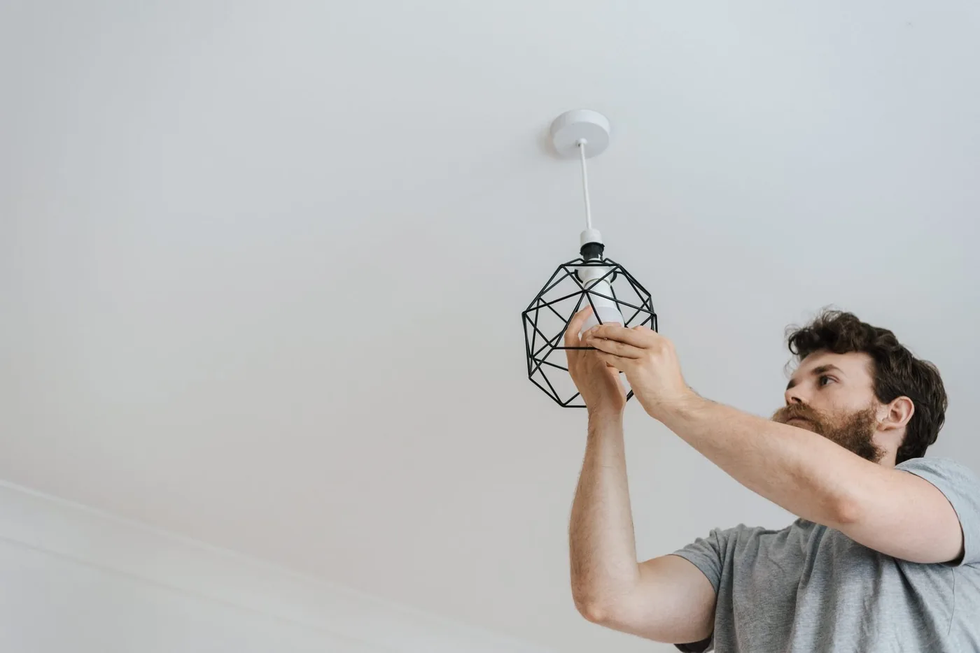 Electrician installing a pendant light fixture on a ceiling